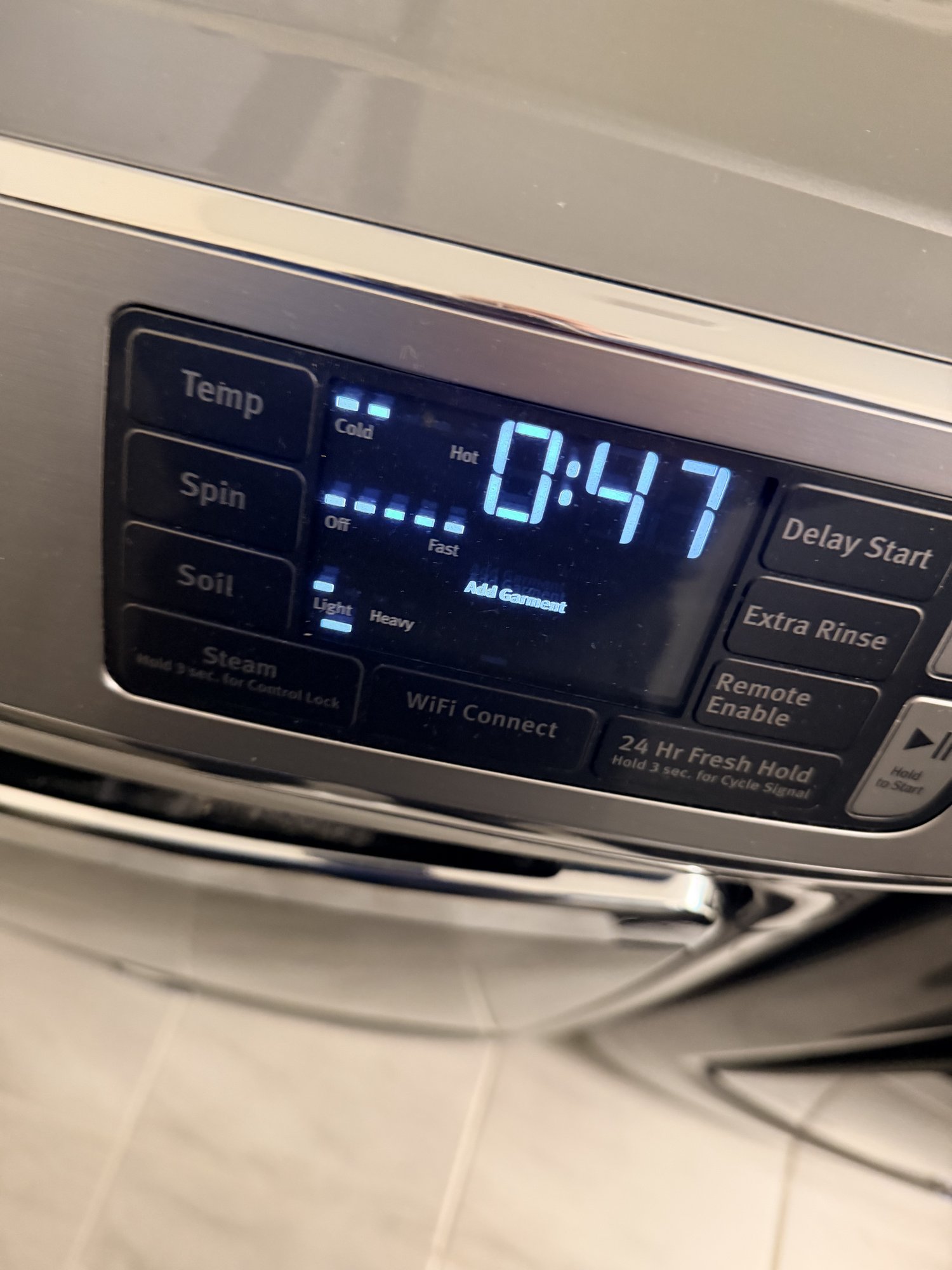 Hands redistributing laundry in an LG front-load washer drum to clear the LE error code