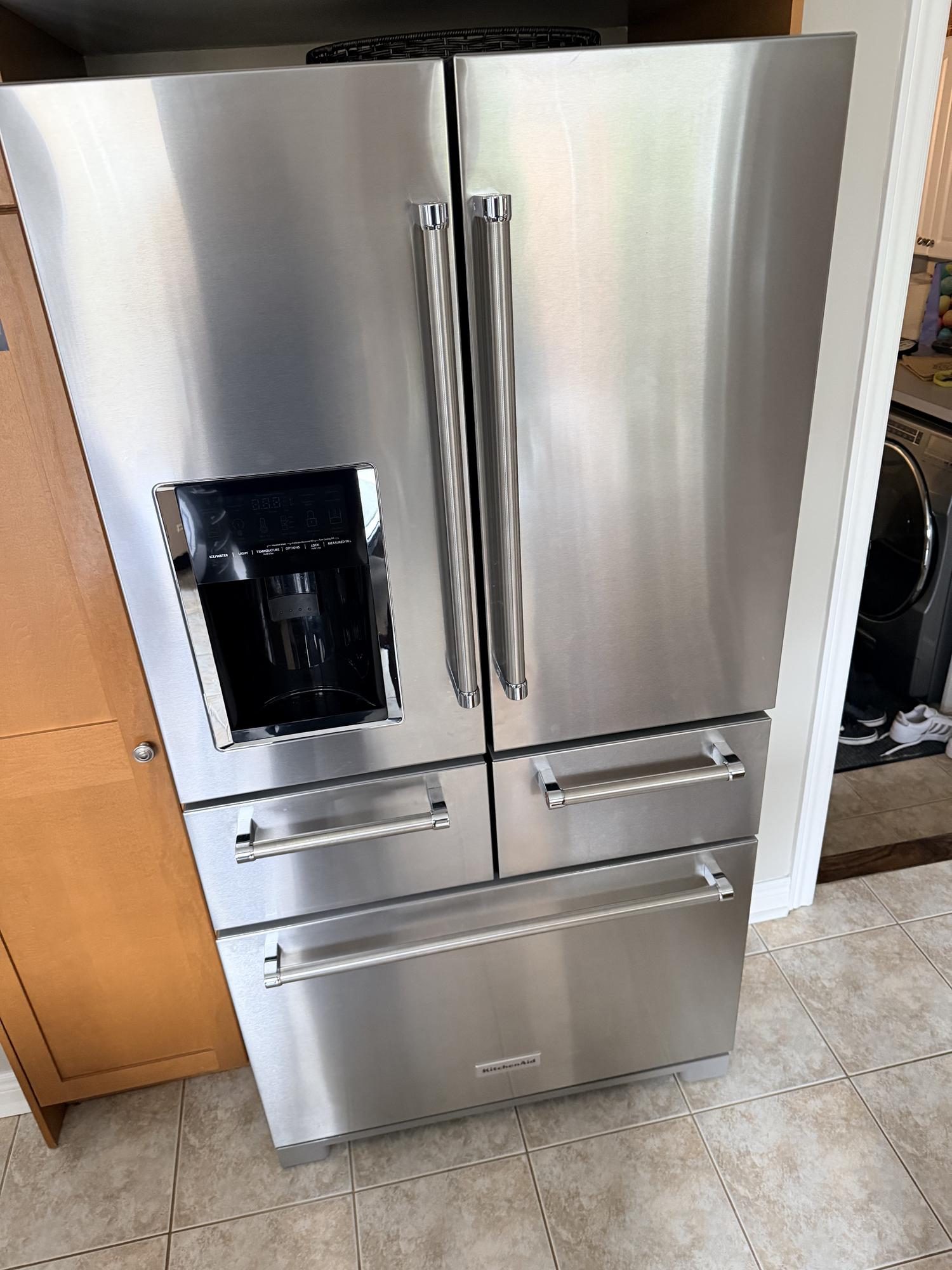 Samsung French-door refrigerator pulled away from the wall and unplugged during a manual defrost with towels at the base