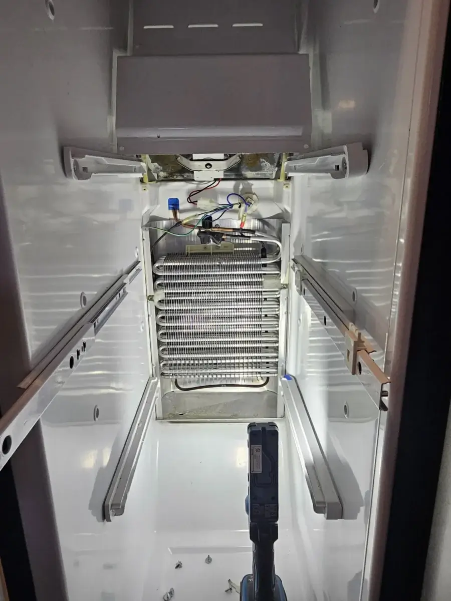 Refrigerator interior with the rear panel area exposed, where the defrost drain backs up when clogged