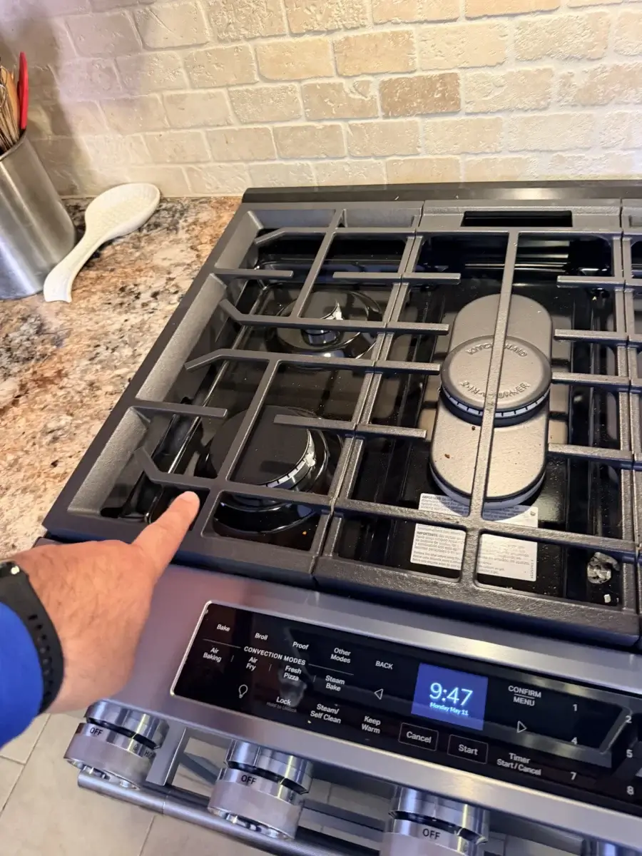Hand pointing at a stainless-steel gas stove burner in a Bradford, Ontario kitchen